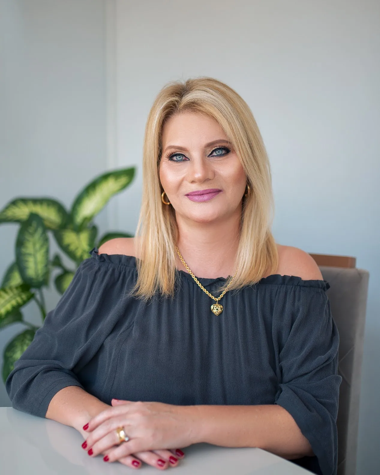 Luciana Meirelles sorrindo, sentada à mesa de reuniões do escritório